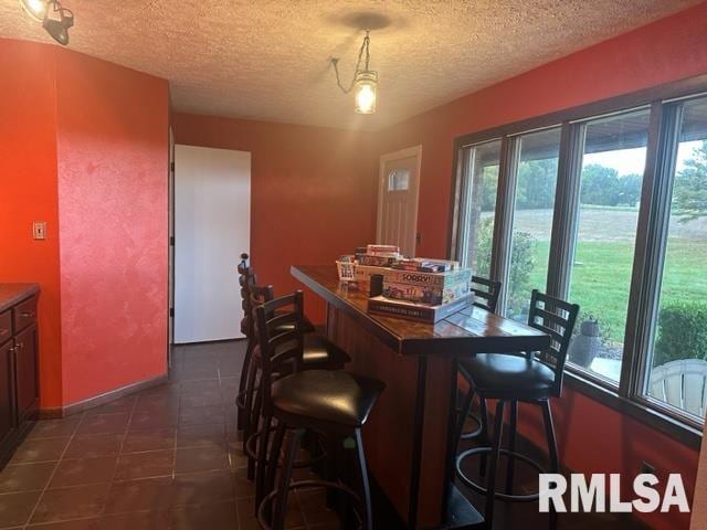 dining area with a textured ceiling and dark tile floors