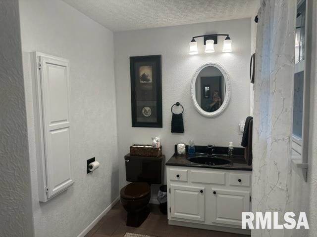 bathroom featuring a textured ceiling, vanity, and toilet