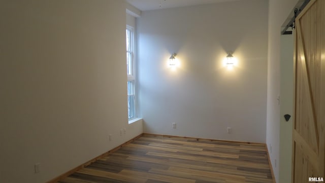 unfurnished room featuring a barn door and dark wood-type flooring