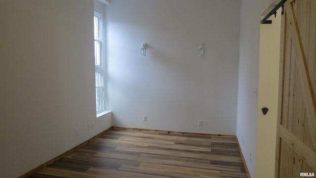 spare room with a barn door and dark wood-type flooring