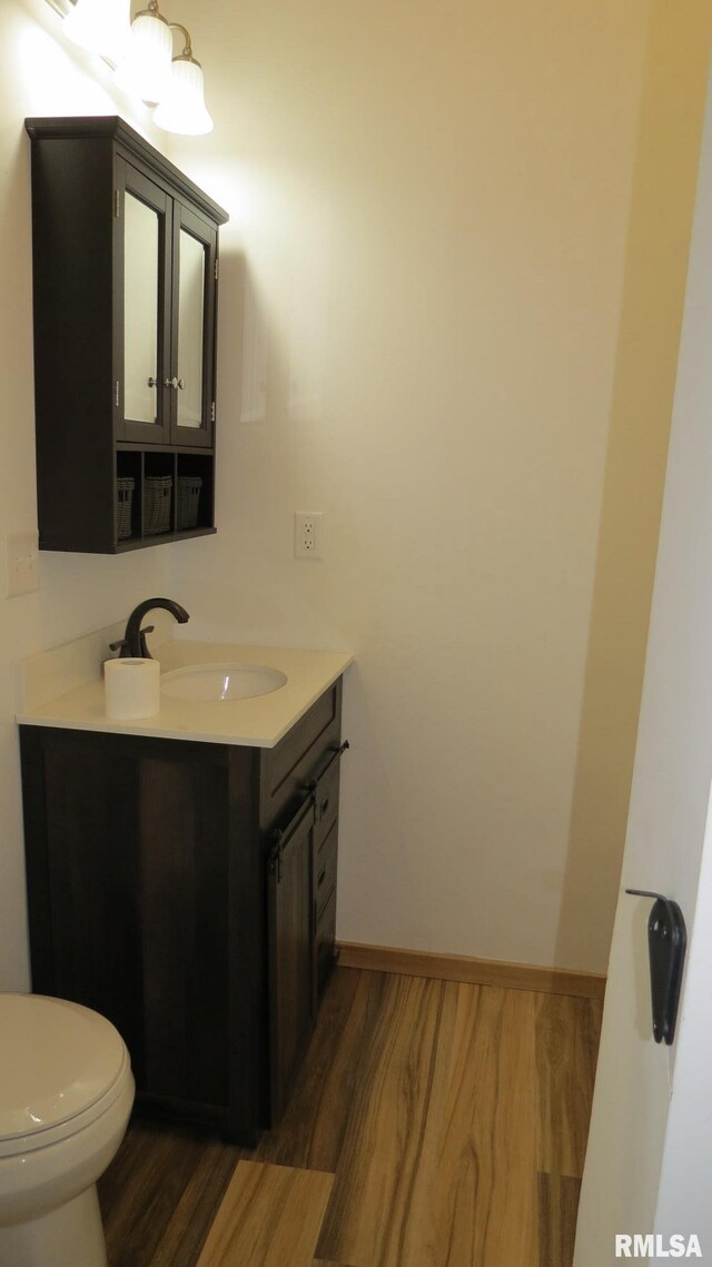 bathroom with toilet, vanity, and hardwood / wood-style flooring