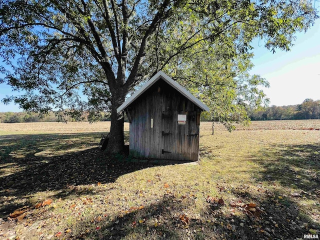 view of outbuilding with a lawn and a rural view