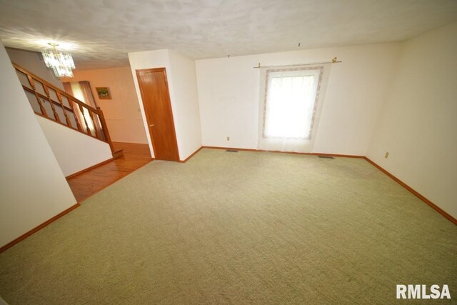 carpeted empty room with an inviting chandelier