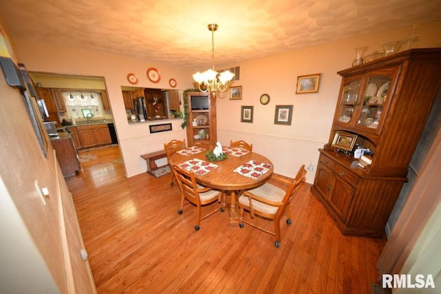 dining area featuring light hardwood / wood-style floors, an inviting chandelier, and sink