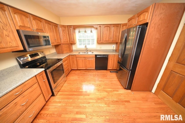 kitchen with appliances with stainless steel finishes, light hardwood / wood-style floors, and sink