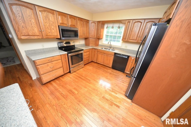 kitchen with stainless steel appliances, light hardwood / wood-style flooring, and sink