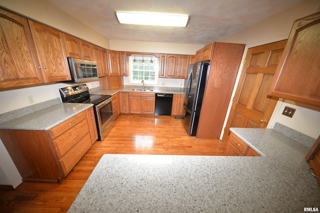 kitchen with appliances with stainless steel finishes, light hardwood / wood-style flooring, and sink