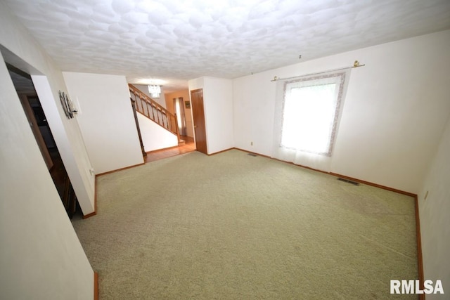 unfurnished room with light colored carpet and a textured ceiling