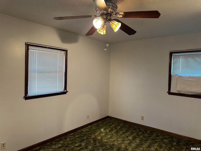 spare room with ceiling fan, dark carpet, and a textured ceiling