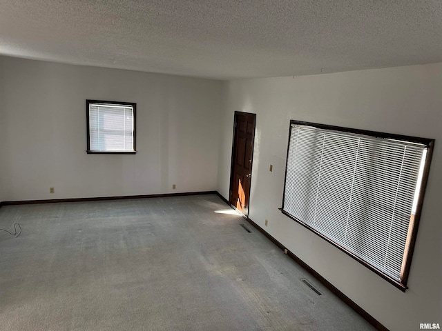 carpeted spare room with a textured ceiling