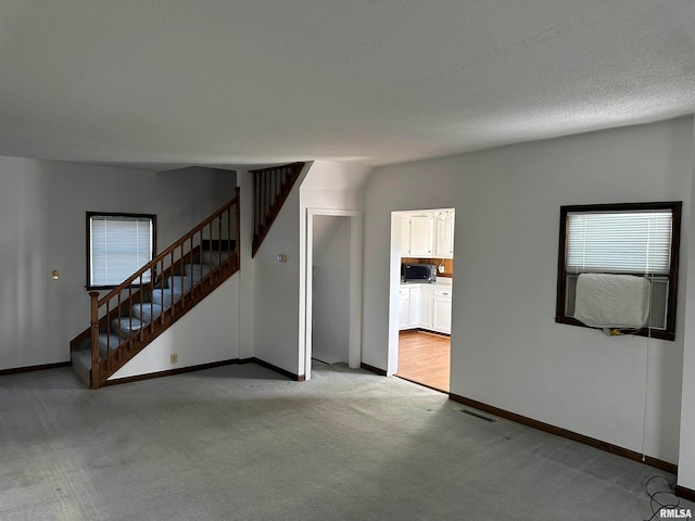 unfurnished living room featuring light colored carpet and a textured ceiling