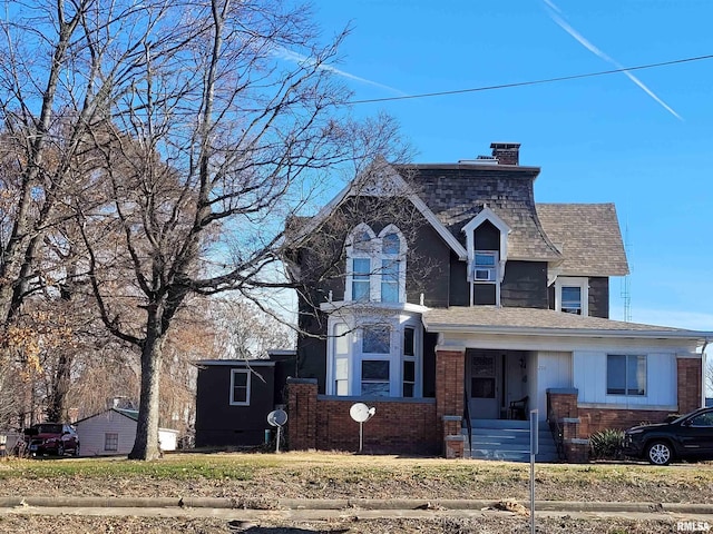 view of front of house featuring a shingled roof, a chimney, and brick siding