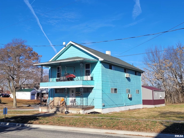 view of front facade featuring covered porch, a balcony, and a front yard