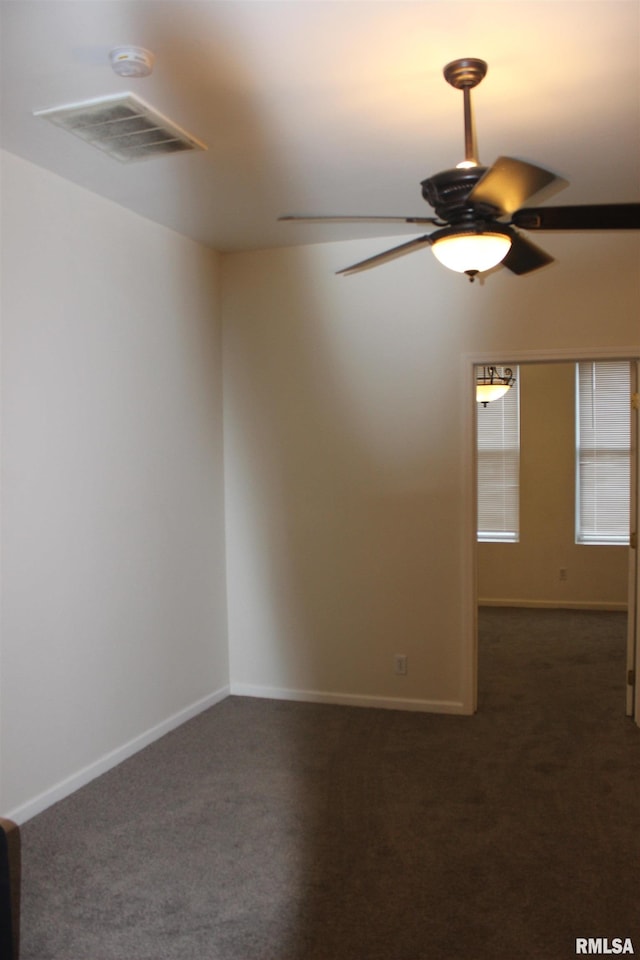 spare room featuring ceiling fan and dark carpet