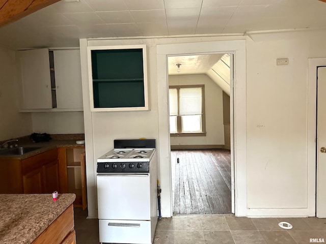 kitchen with lofted ceiling, dark tile flooring, electric range, and sink