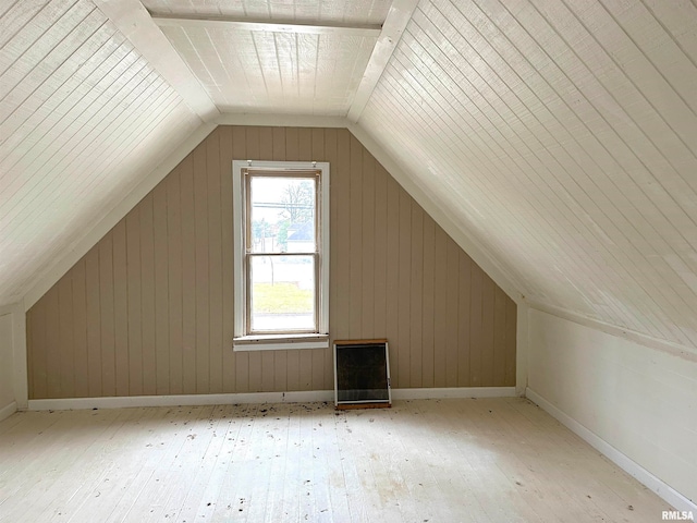 additional living space featuring light wood-type flooring, wooden walls, and vaulted ceiling