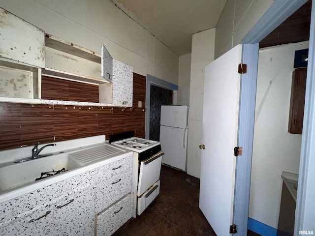 kitchen featuring white appliances, dark tile flooring, sink, and tile walls