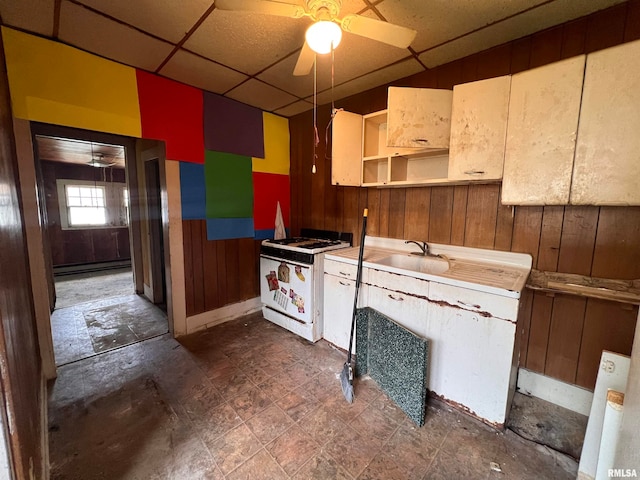 kitchen with a paneled ceiling, wood walls, a baseboard radiator, sink, and white range with gas stovetop