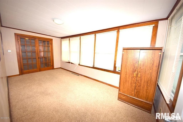 interior space with french doors, light colored carpet, and a closet