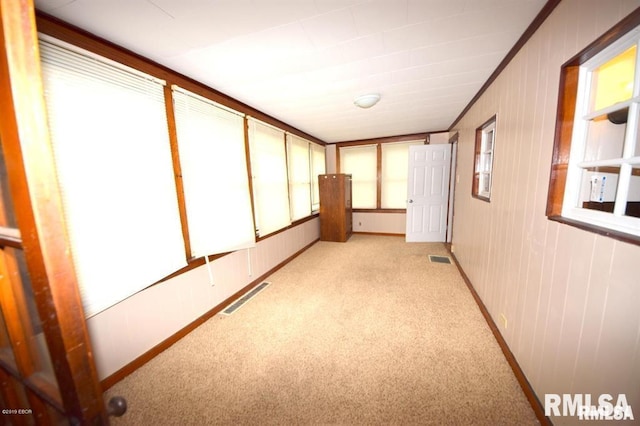 corridor with light carpet, ornamental molding, and a healthy amount of sunlight