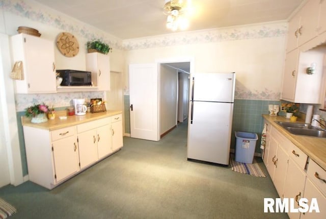 kitchen with light colored carpet, white refrigerator, white cabinets, and sink