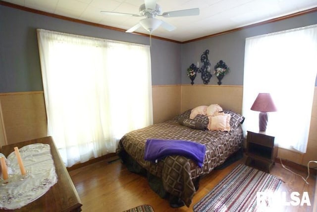 bedroom featuring ornamental molding, hardwood / wood-style floors, multiple windows, and ceiling fan