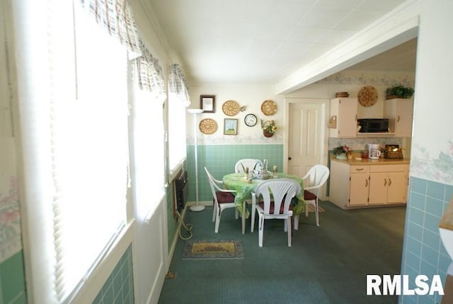 dining room with crown molding, dark colored carpet, and a healthy amount of sunlight