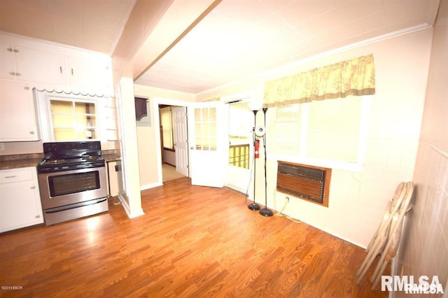 kitchen with light hardwood / wood-style floors, stainless steel range, heating unit, ornamental molding, and white cabinets