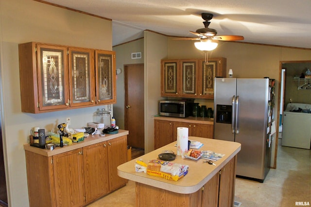 kitchen with lofted ceiling, ceiling fan, appliances with stainless steel finishes, a kitchen island, and washer / clothes dryer