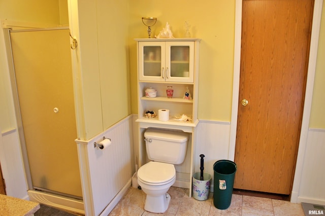 bathroom with toilet, tile floors, and a shower with shower door