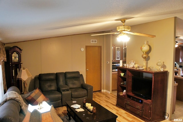 living room with a textured ceiling, ceiling fan, and light wood-type flooring