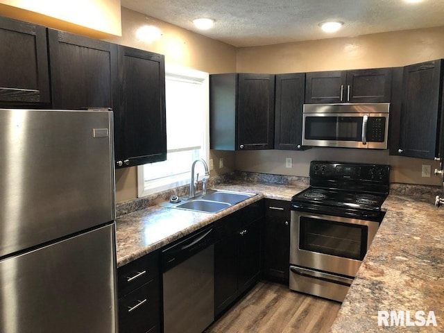 kitchen featuring light wood-type flooring, appliances with stainless steel finishes, a textured ceiling, and sink