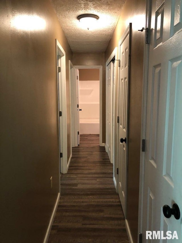 hall featuring a textured ceiling and dark wood-type flooring