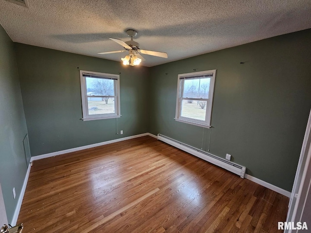 spare room with hardwood / wood-style flooring, a baseboard radiator, ceiling fan, and plenty of natural light