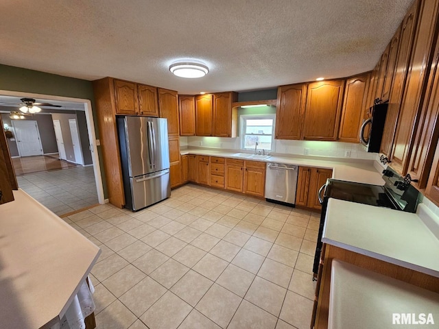 kitchen featuring light tile patterned flooring, sink, a textured ceiling, ceiling fan, and stainless steel appliances