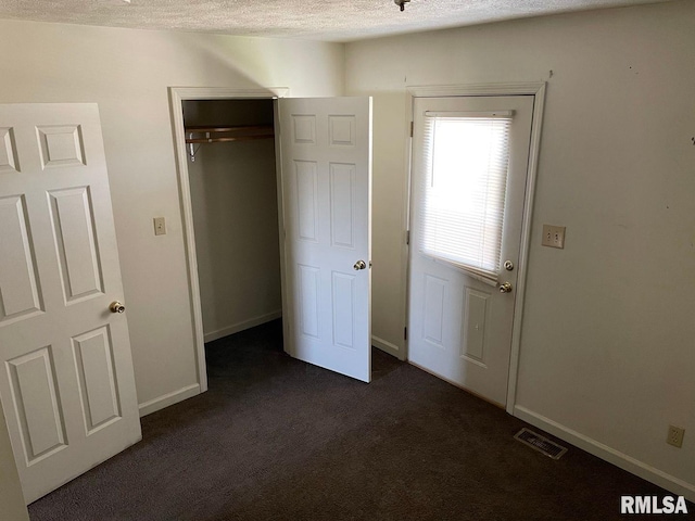 unfurnished bedroom featuring a closet, dark carpet, and a textured ceiling