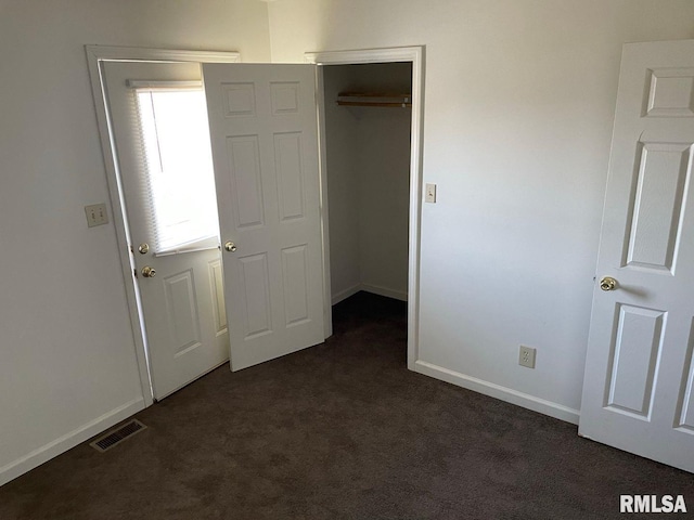 unfurnished bedroom with a closet and dark colored carpet