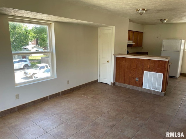 kitchen with kitchen peninsula, a textured ceiling, and white fridge