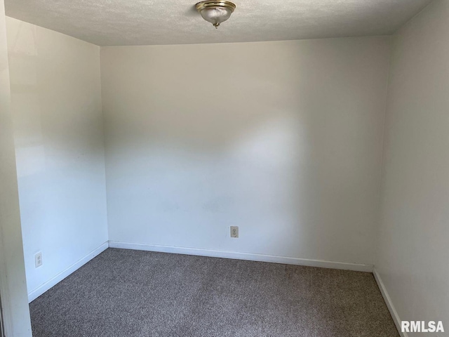 unfurnished room featuring a textured ceiling and dark colored carpet