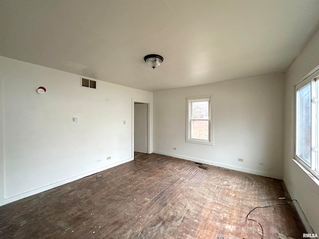 spare room with dark hardwood / wood-style flooring and a wealth of natural light