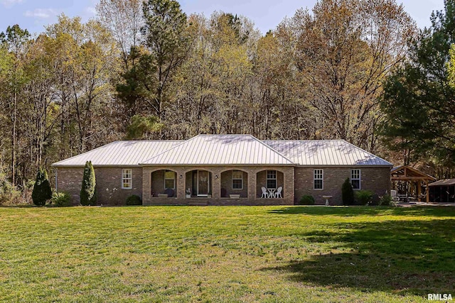 ranch-style house featuring metal roof, brick siding, covered porch, and a front yard