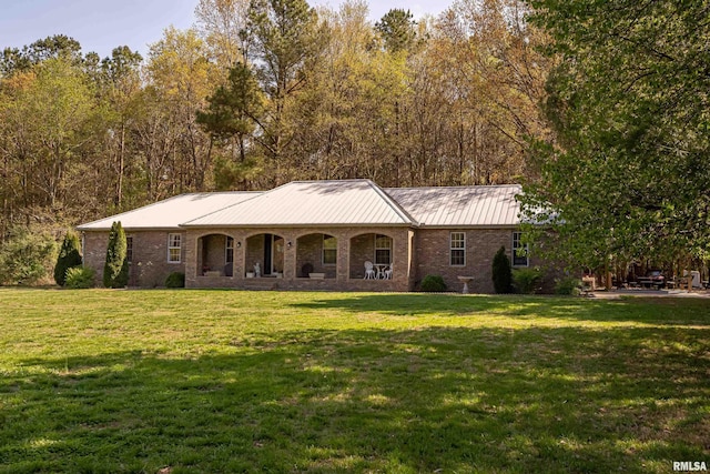 ranch-style home with metal roof, brick siding, a front lawn, and a standing seam roof