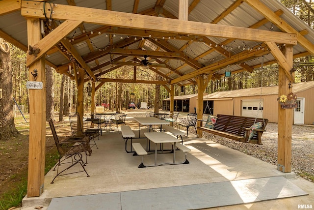 view of patio / terrace featuring a garage, ceiling fan, a gazebo, and an outdoor structure