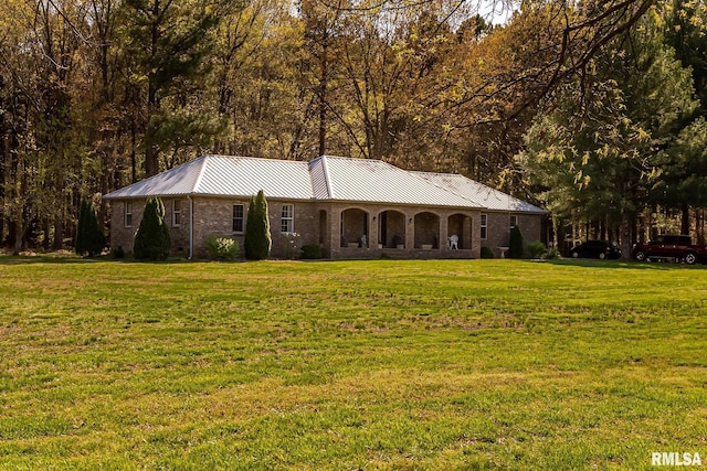 single story home featuring a front yard, brick siding, and metal roof