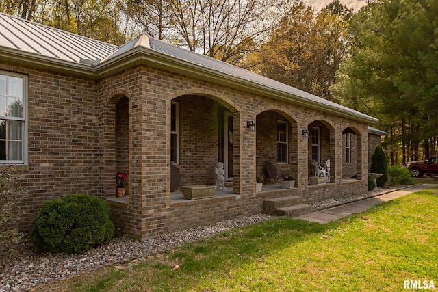 view of side of home with a lawn and covered porch