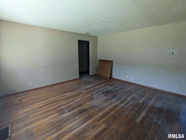 empty room with a textured ceiling and dark hardwood / wood-style floors