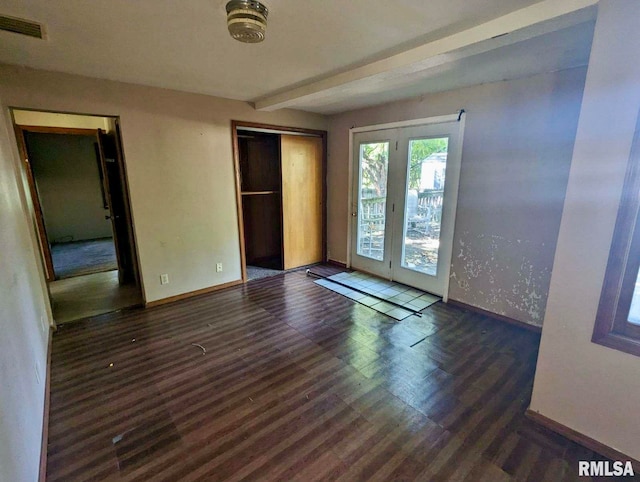 unfurnished bedroom with beam ceiling, a closet, dark wood-type flooring, and access to outside