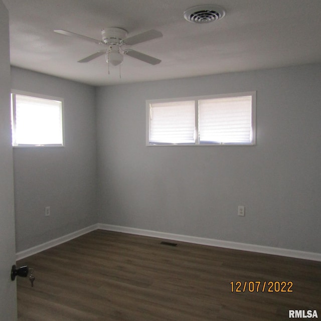 empty room with dark hardwood / wood-style floors, ceiling fan, and a wealth of natural light