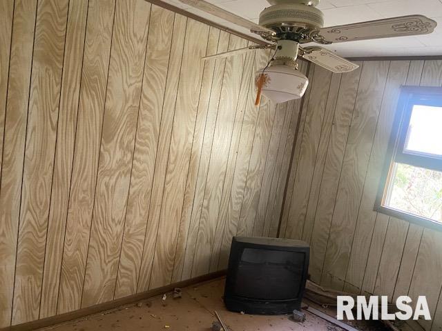 spare room featuring a wood stove and ceiling fan