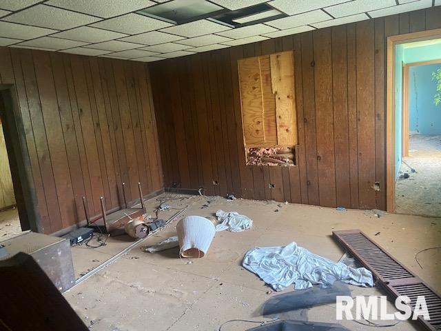 miscellaneous room featuring wooden walls and a drop ceiling